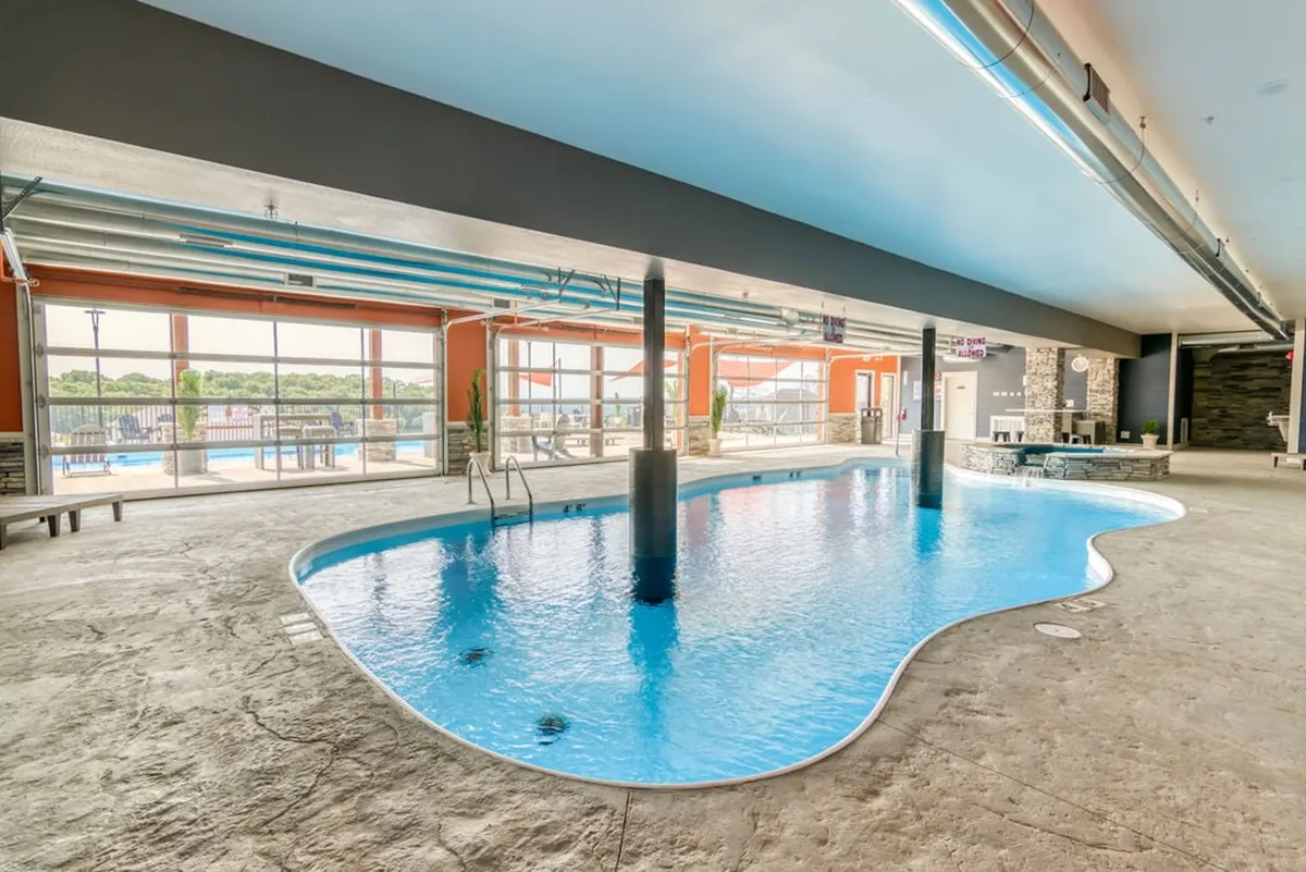 A spacious indoor swimming pool illuminated by natural light streaming through large windows. The modern decor and tranquil setting highlight year-round swimming options and a refreshing place to relax, regardless of the weather.
