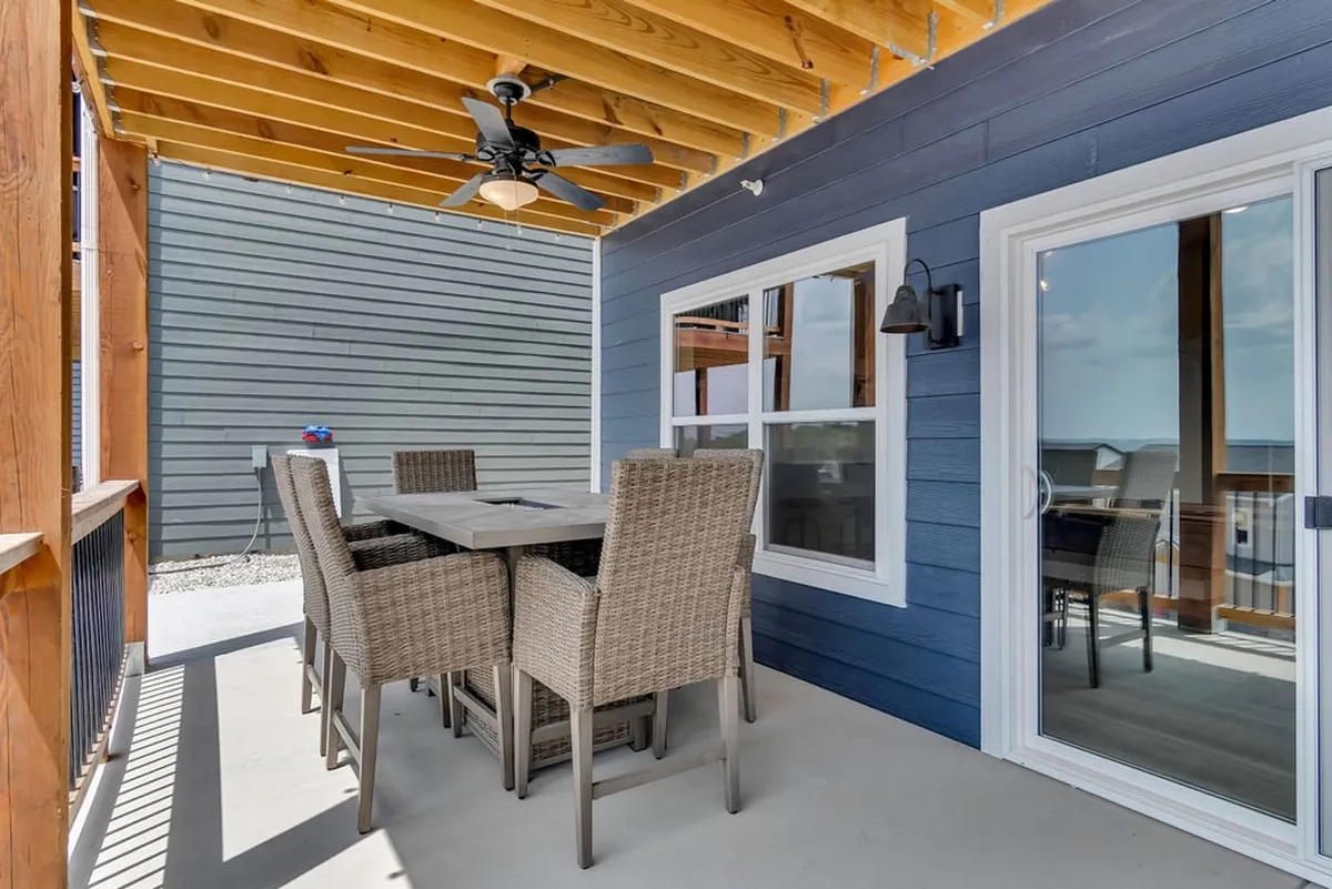 A tastefully furnished exterior dining space featuring a dining table, wicker chairs, and a ceiling fan. The setup is perfect for enjoying meals or relaxing outdoors while taking in the fresh air and beautiful surroundings, evoking leisurely mornings or sunset dinners.