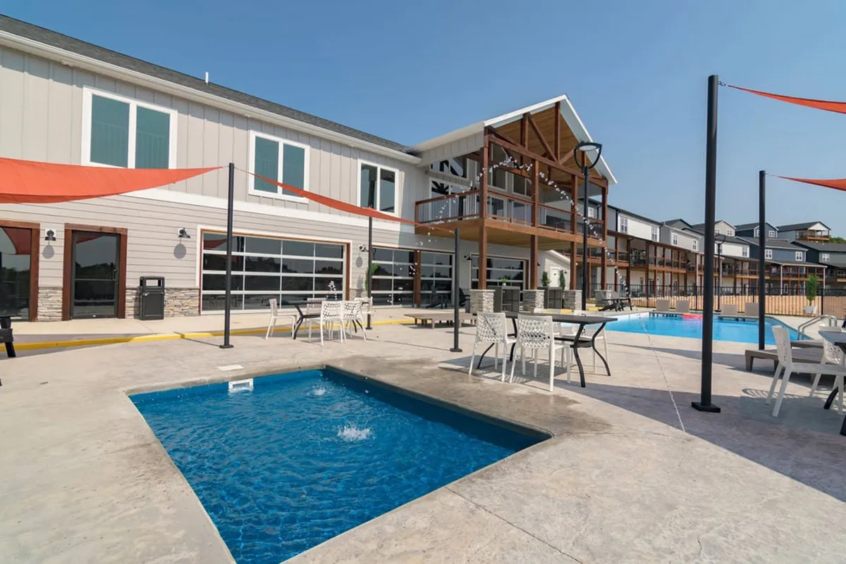 This image showcases the resort's outdoor swimming pool and hot tub area, flanked by outdoor seating and building facade. String lights suggest a welcoming, communal atmosphere perfect for both daytime swims and evening gatherings.