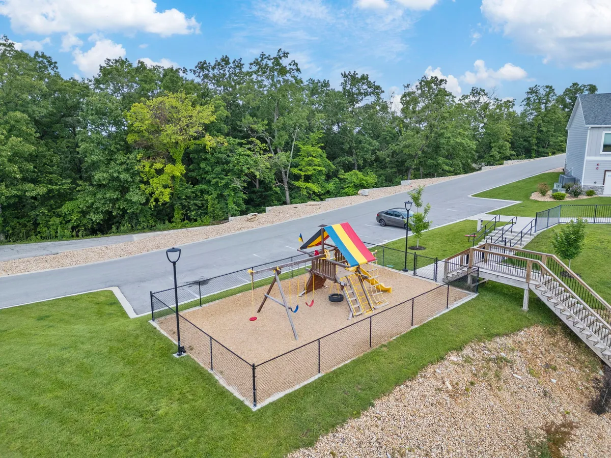 A vibrant playground structure with swings and a colorful roof, set amidst lush greenery. Children are seen playing and families gather around, capturing joy and community spirit.