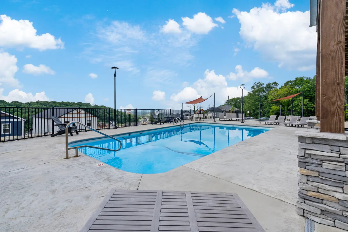An outdoor swimming pool surrounded by lounge chairs and landscaped views, set against the backdrop of the community. The pool deck offers ample space for swimming, sunbathing, social gatherings, and enjoying the sunset over the water.